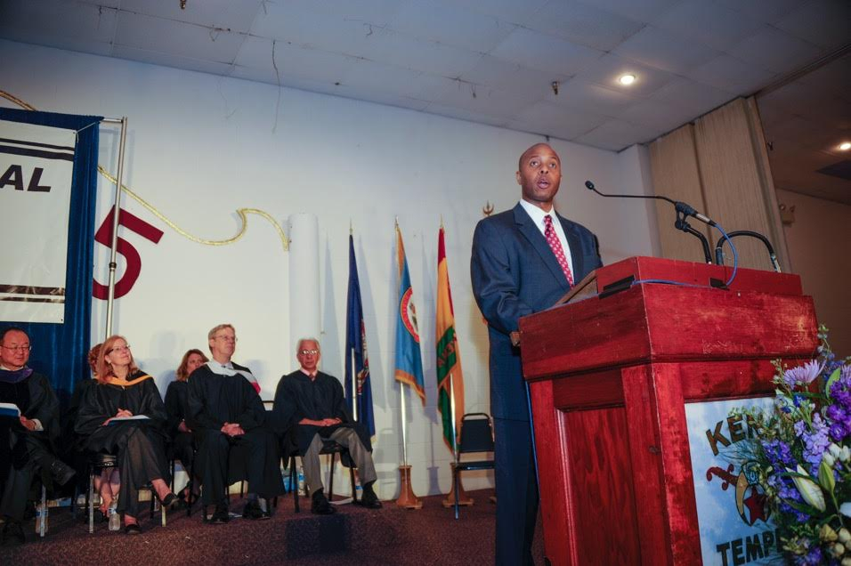 A man in a suit is speaking at a podium.