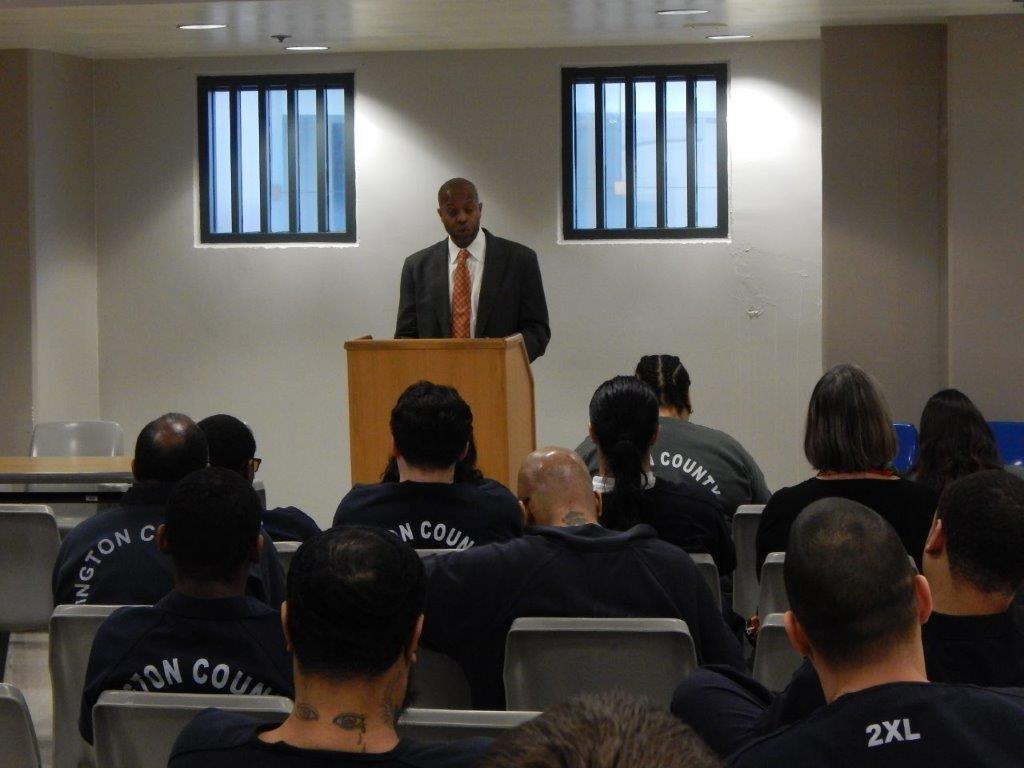 A man is giving a lecture to inmates.